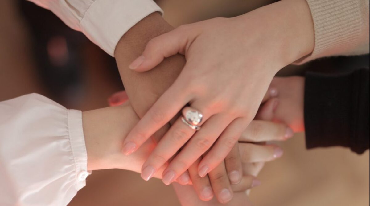 Crop friends stacking hands together