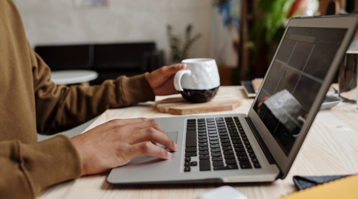 Person using macbook pro on brown wooden table