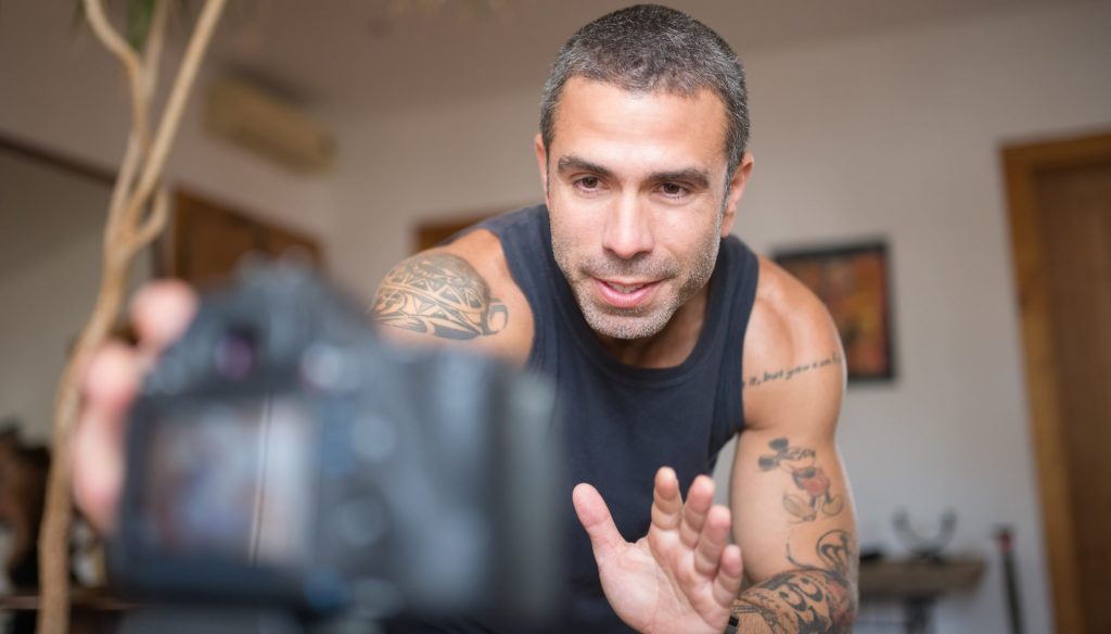 A low angle shot of a tattooed man in tank top