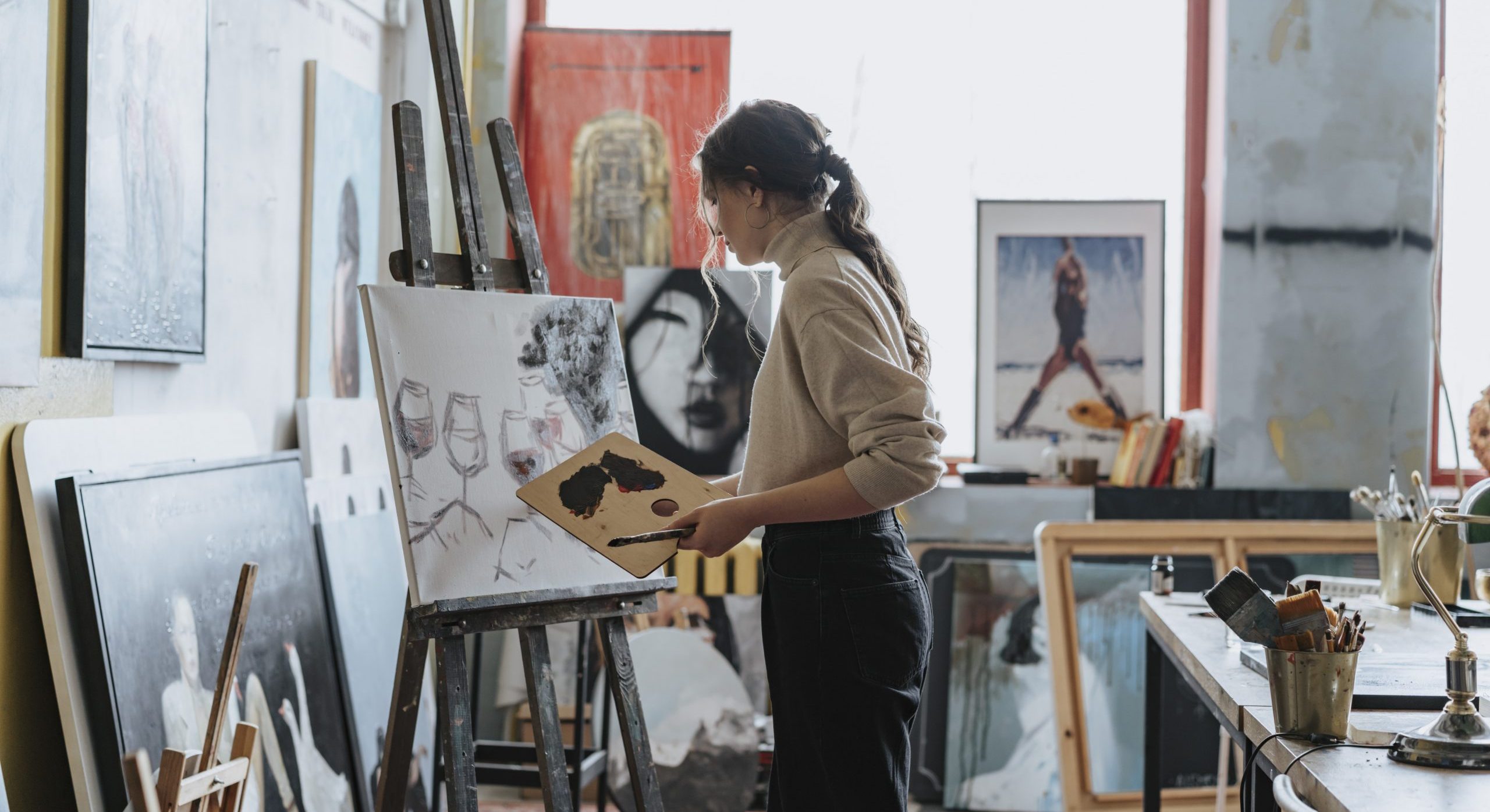 A woman painting wine glasses on a canvas