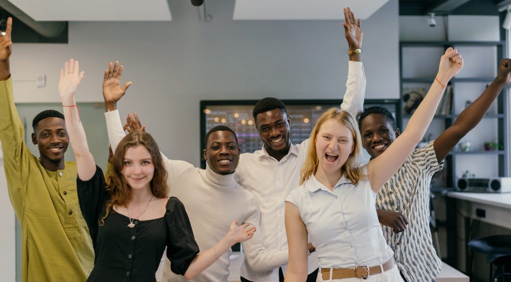 Employees raising their hands while smiling at the camera