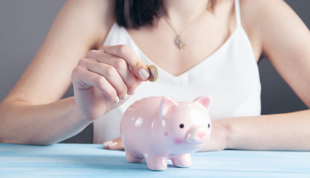 woman in white tank top holding pink pig figurine