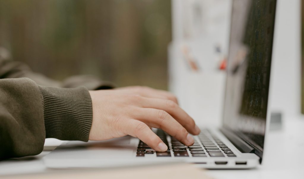 Hands typing on a laptop in close up photography