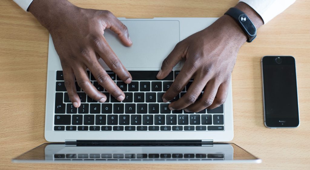 person's hand on MacBook near iPhone flat lay photography